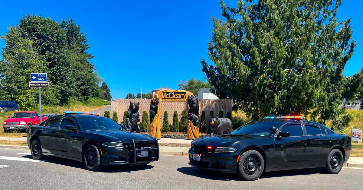 Two City of McCleary police cruisers in front of the Bear Festival sign